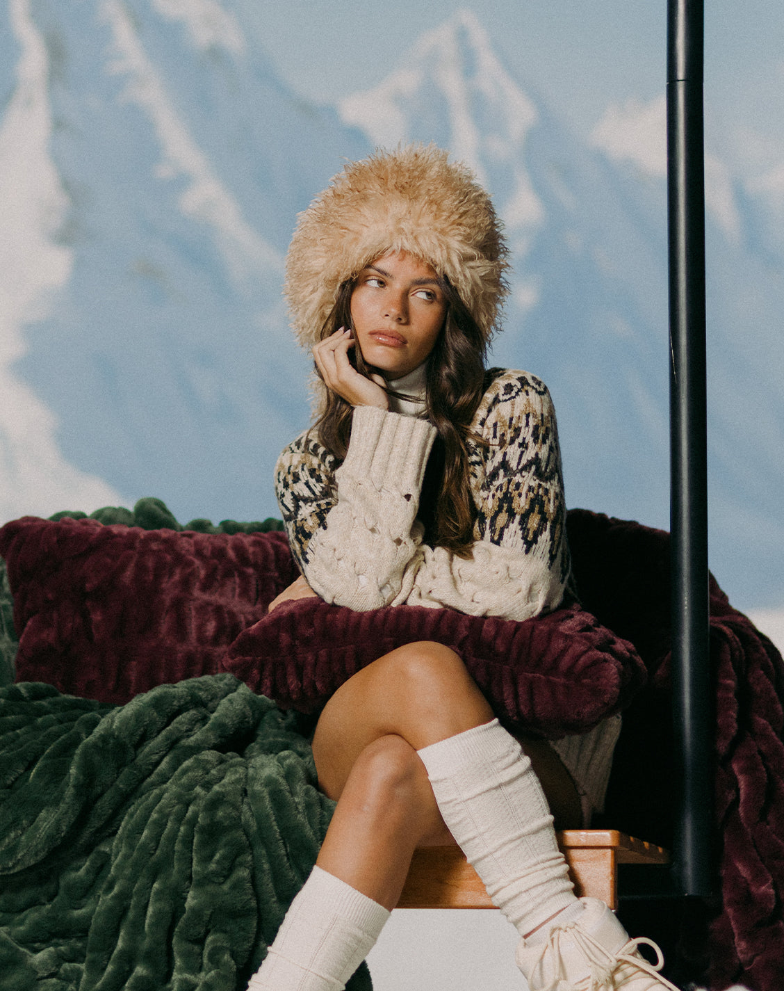 Woman in winter clothing sitting on a bench with mountains in the background