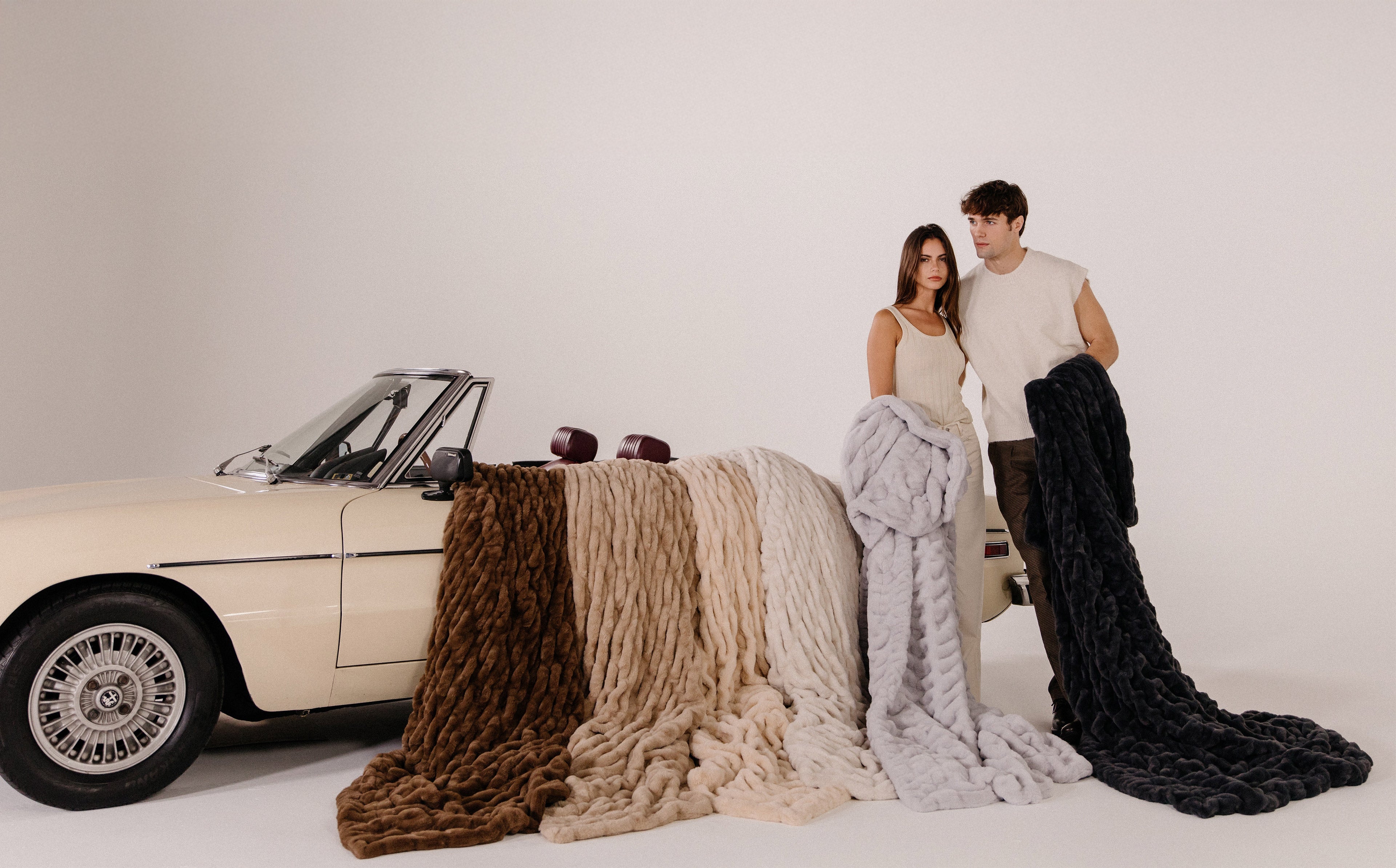 Two people holding textured blankets in their hands and striking a stylish pose.