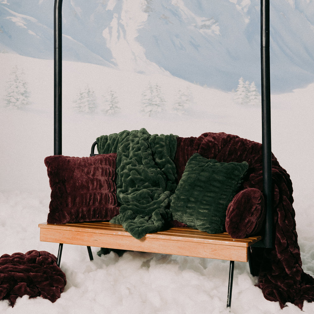 Wooden swing with green and maroon cushions against a snowy mountain backdrop