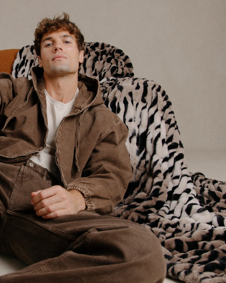 Man with a tiger stripe patterned fabric draped behind his head against a neutral background
