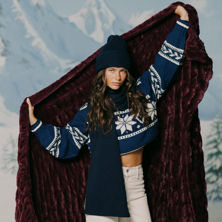 Woman holding a dark red blanket with a mountainous background