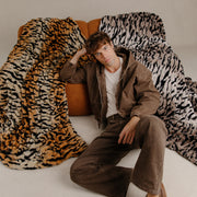 Man sitting on a couch with a tiger print blanket