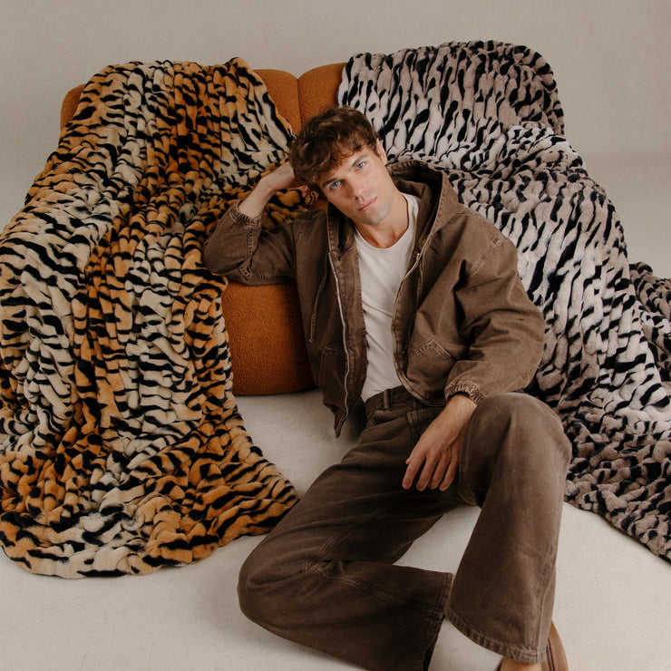 Man sitting on a couch with a tiger print blanket