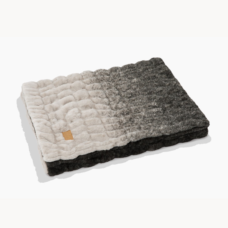 Quilted blanket with a gradient pattern on a white background