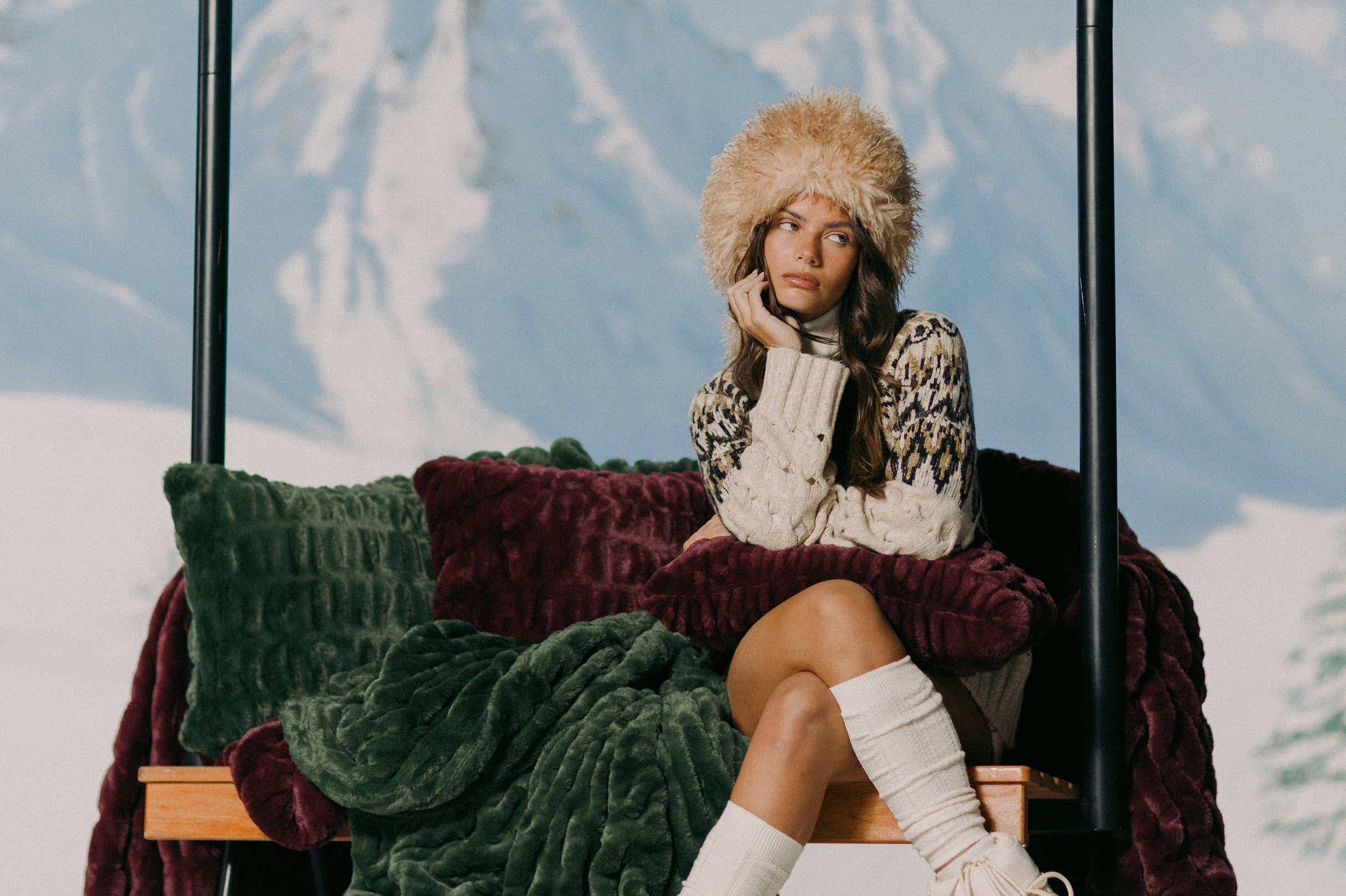 Woman in winter clothing sitting on a bench with snowy mountains in the background