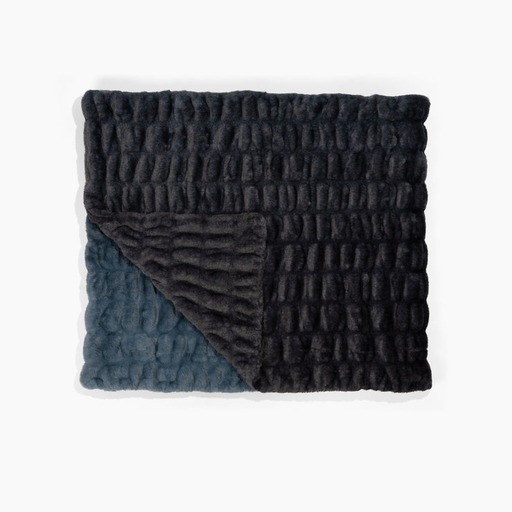 Folded textured blanket with two different color patterns on a white background