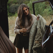 Woman holding a blanket next to an open car door in a natural setting